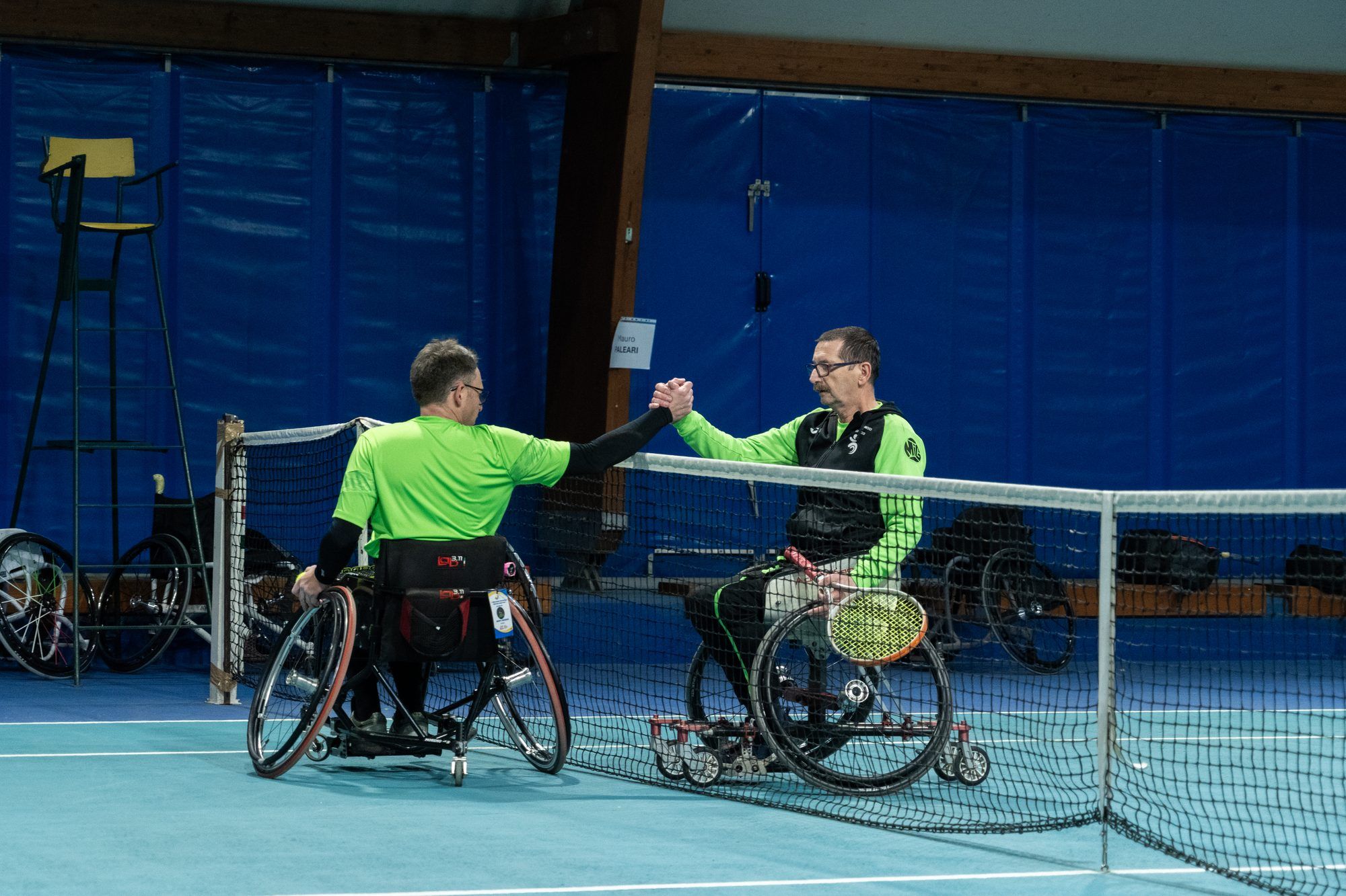 Due tennisti in carrozzina si stringono la mano a rete a fine partita.